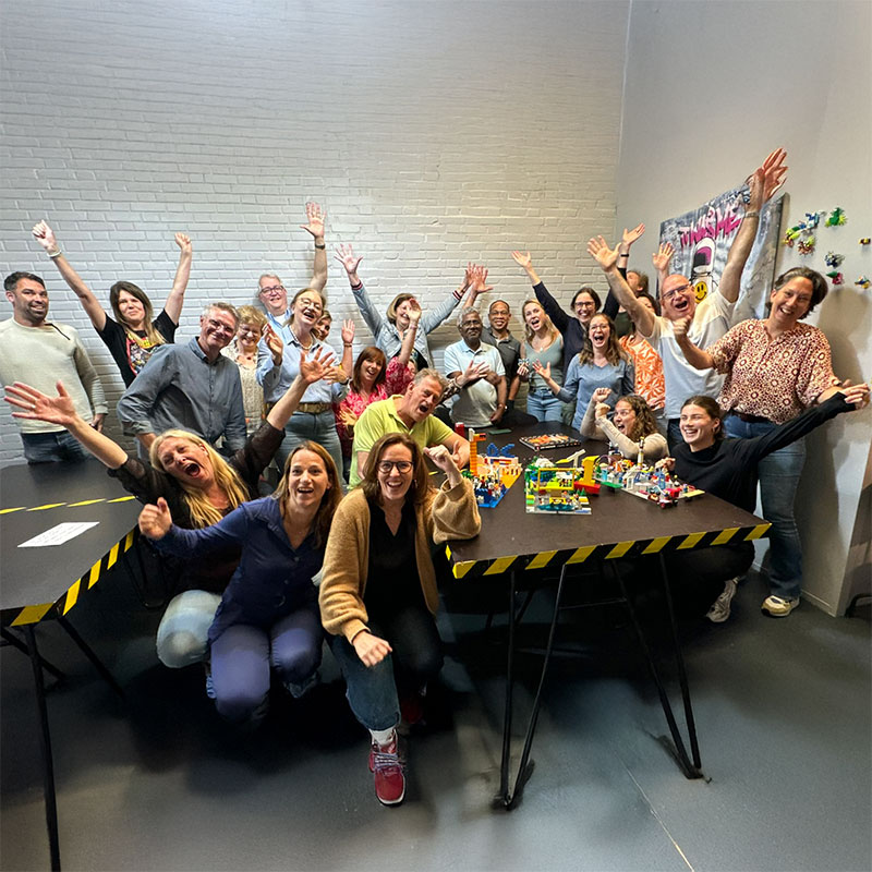 een blije groep deelnemers aan een workshop van THE POWER OF BRICKS