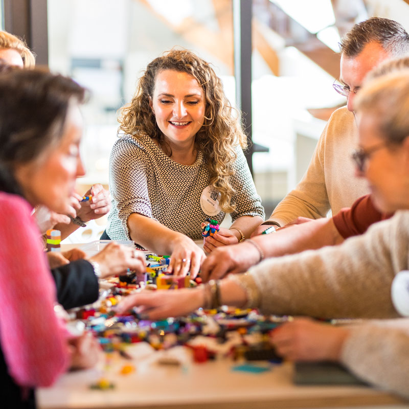 een blije groep deelnemers aan een workshop van THE POWER OF BRICKS
